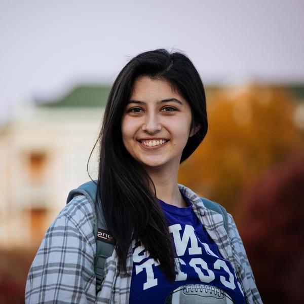 Student with dark hair smiles at camera.